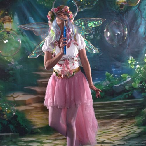 Fairy blowing bubbles with a beautiful fairy garden background