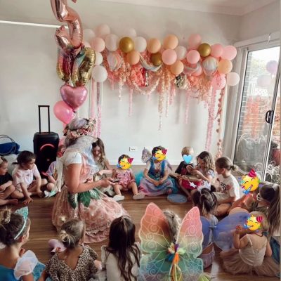 Kids sitting in a circle playing a games at a fairy party.