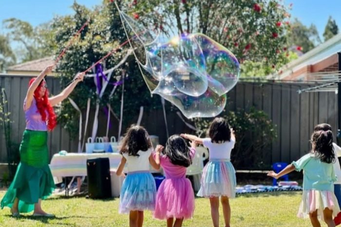 Children running towards a giant bubble during an interactive bubble party in Sydney