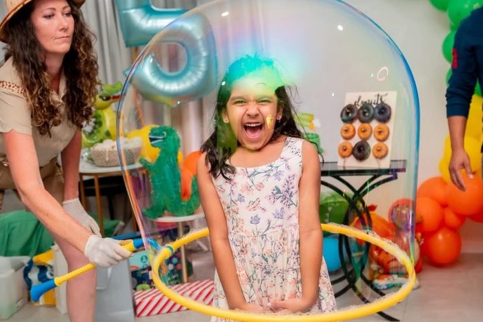 Child standing inside a giant bubble during an interactive bubble party in Sydney.
